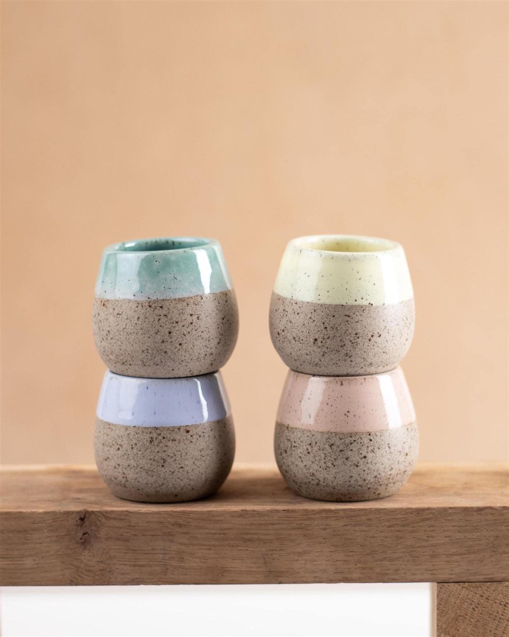 Four ceramic espresso cups in a soft palette, arranged in warm sunlight