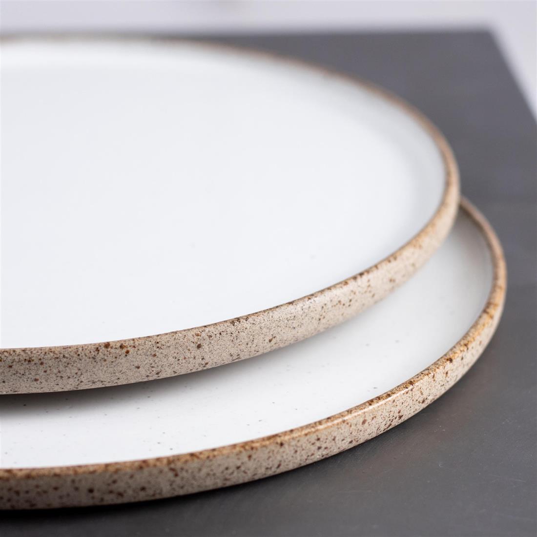 Ceramic plates with softly speckled rims and a warm white glaze